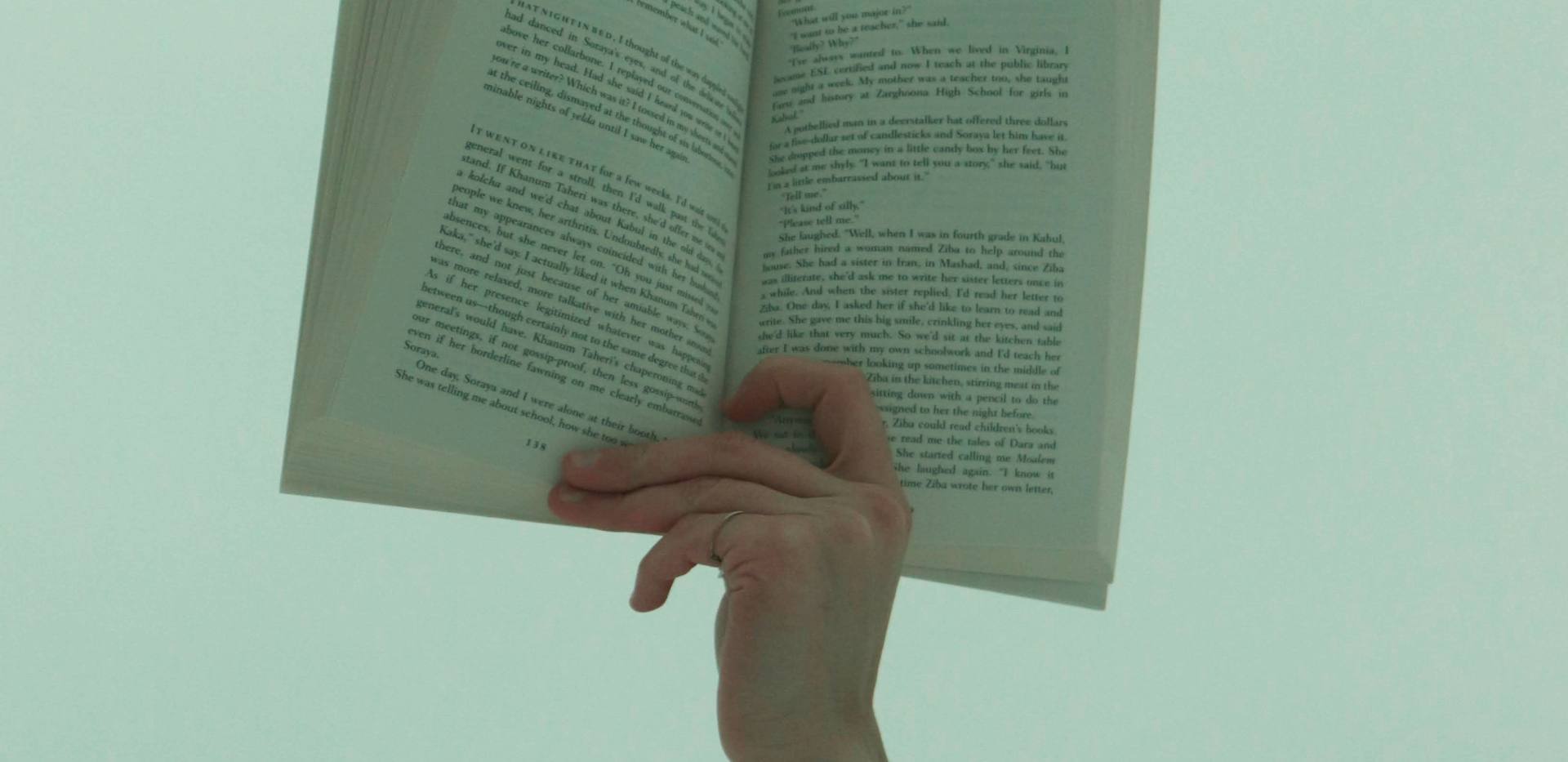 Hand h&auml;lt Buch vor einen gr&uuml;nen Hintergrund. Foto: r&uuml;veyda/Pexels