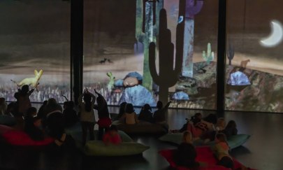 Im Vordergrund sind die Silhouetten von Kindern zu sehen, die die Projektionen im Hintergrund bejubeln.