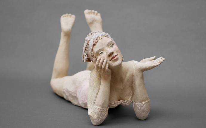 Man sieht eine kleine Figur aus Holz die auf dem Bauch liegt. Man sieht eine kleine Figur aus Holz die auf dem Bauch liegt.