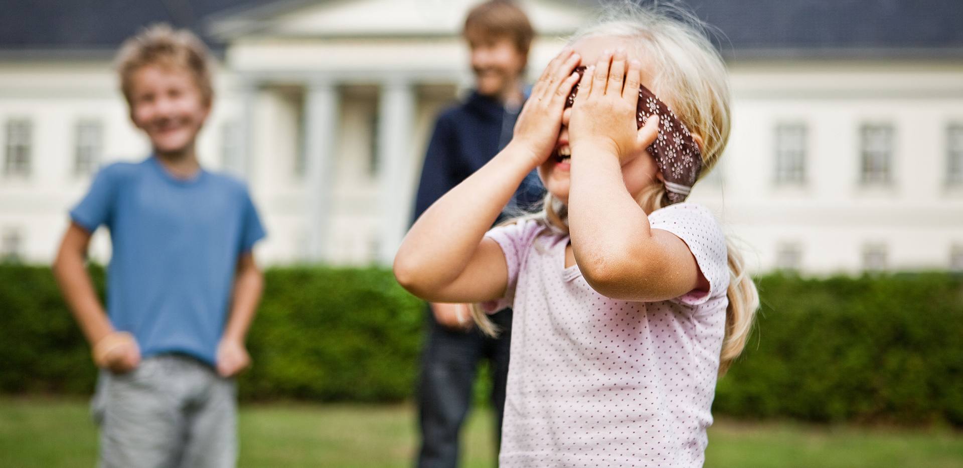 Kinder spielen Blinde Kuh vor einer Sehenswürdigkeit.