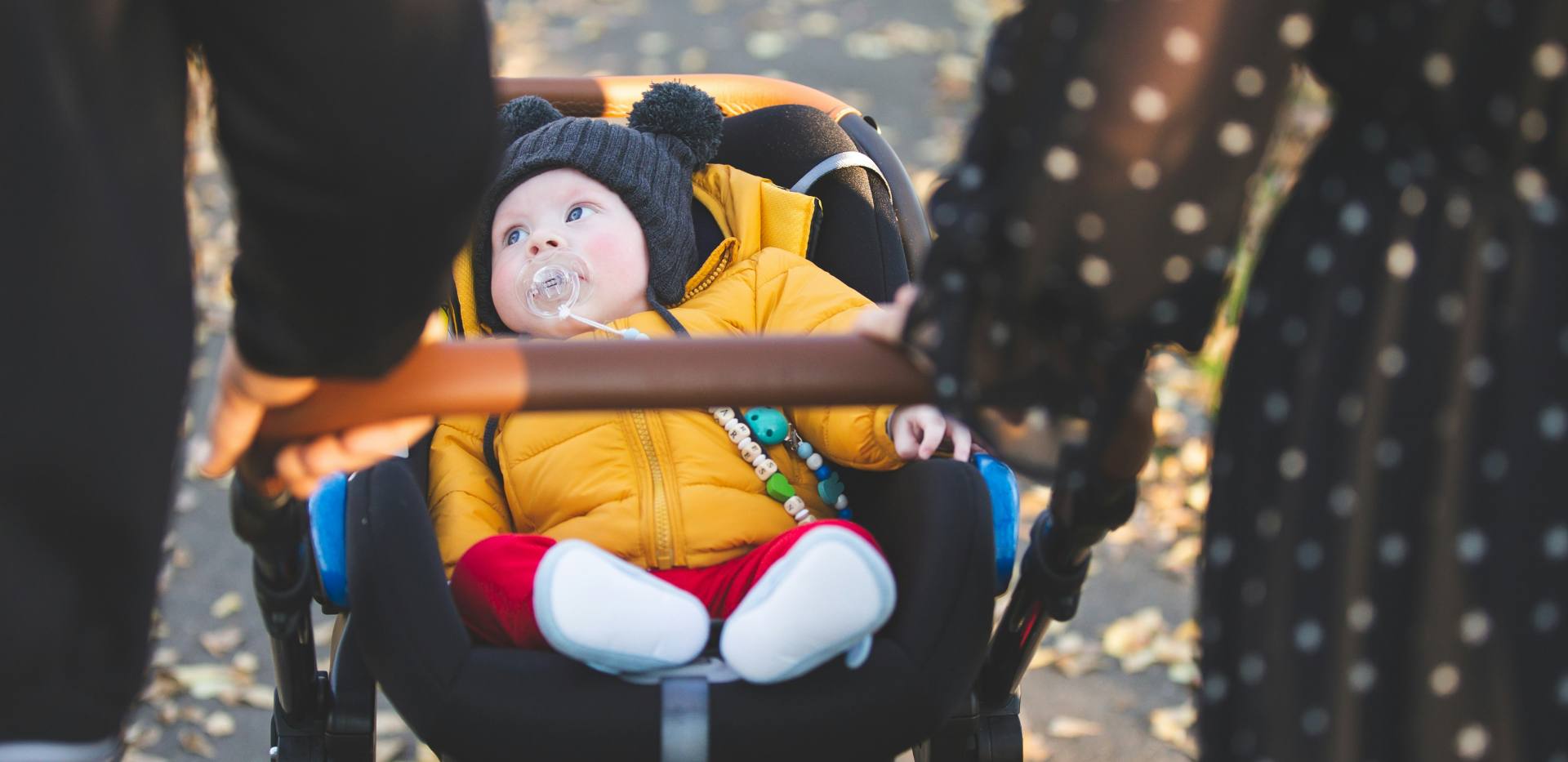 Zwei Personen schieben einen Säugling in einem Kinderwagen Zwei Personen schieben einen Säugling in einem Kinderwagen