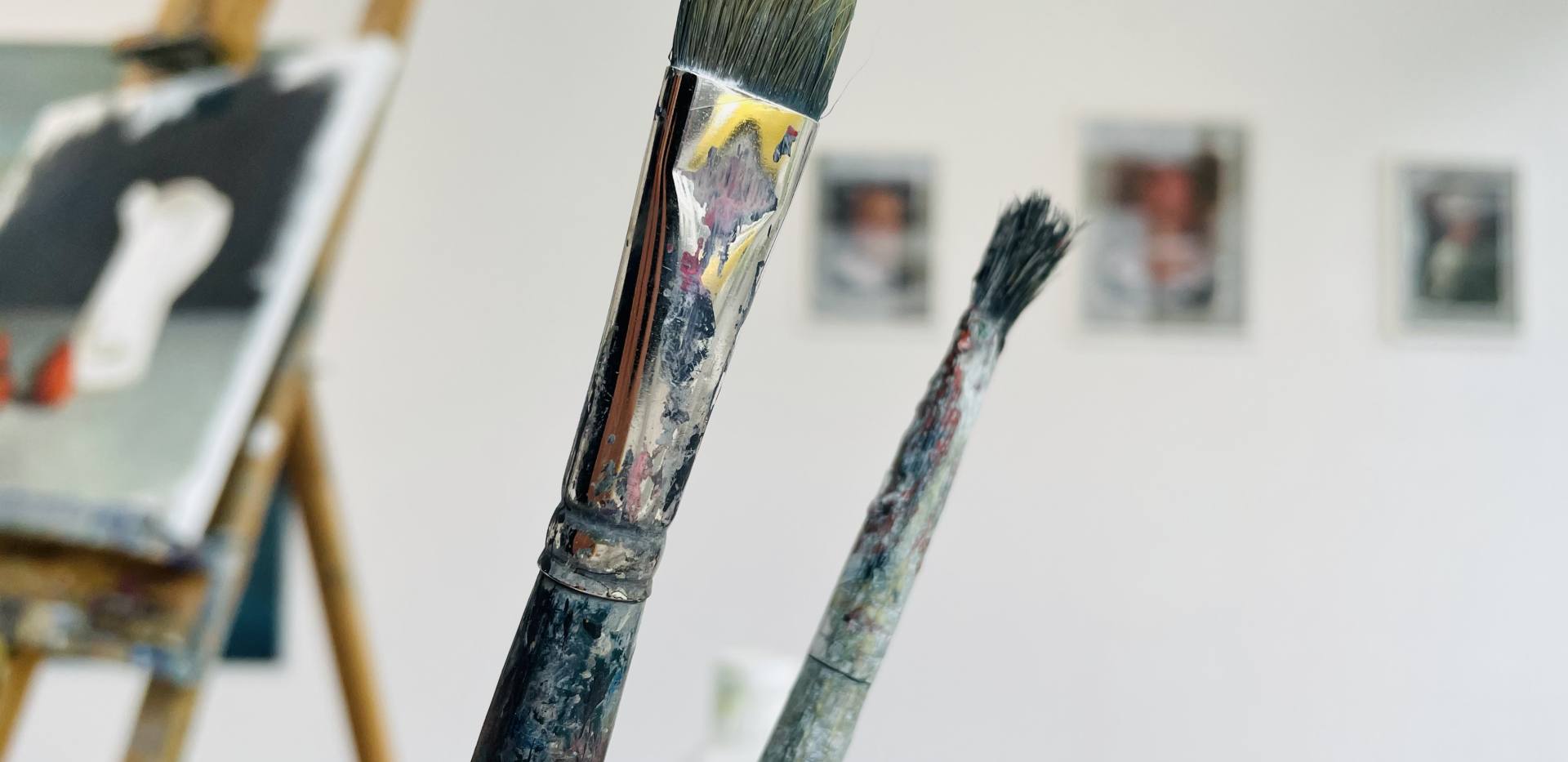 Auf dem Foto befinden sich einige Pinsel, im Hintergrund sieht man Gemälde. Auf dem Foto befinden sich einige Pinsel, im Hintergrund sieht man Gemälde.