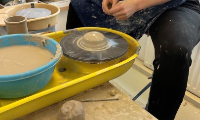 Auf dem Bild sieht man eine Person die an der Drehscheibe ein Stück Ton bearbeitet. Auf dem Bild sieht man eine Person die an der Drehscheibe ein Stück Ton bearbeitet.