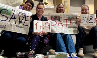 Jenny, Meike, Nele und Gesa halten Zeitung, Heft, Buch hoch mit dem Text "Safe the date, 30.8." Vor ihnen sind Spiele, B&uuml;cher, Stifte