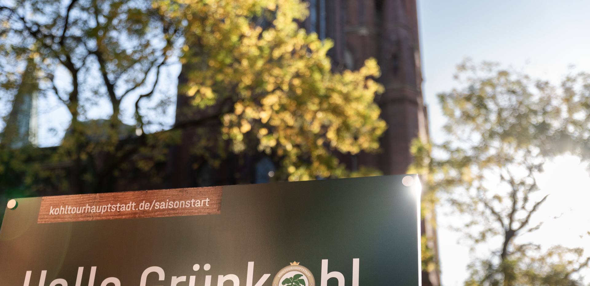 Hinweistafel zu "Hallo Grünkohl" mit Website für Detailinfos und plattdeutschem Spruch.  Hinweistafel zu
