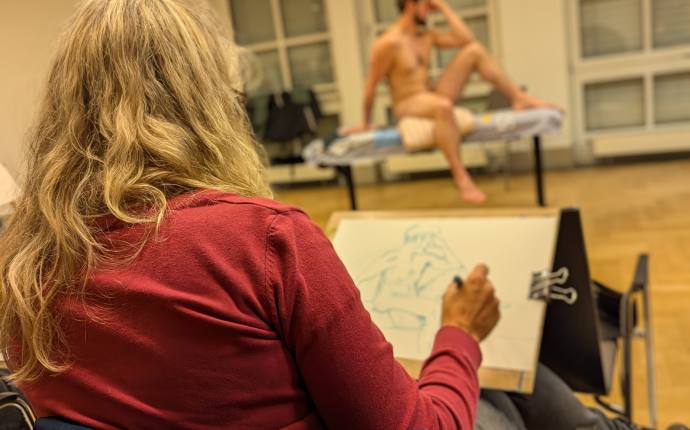 Aktkurs, Zeichnende Teilnehmerin mit Aktmodel im Hintergrund, Foto HJM Aktkurs, Zeichnende Teilnehmerin mit Aktmodel im Hintergrund, Foto HJM
