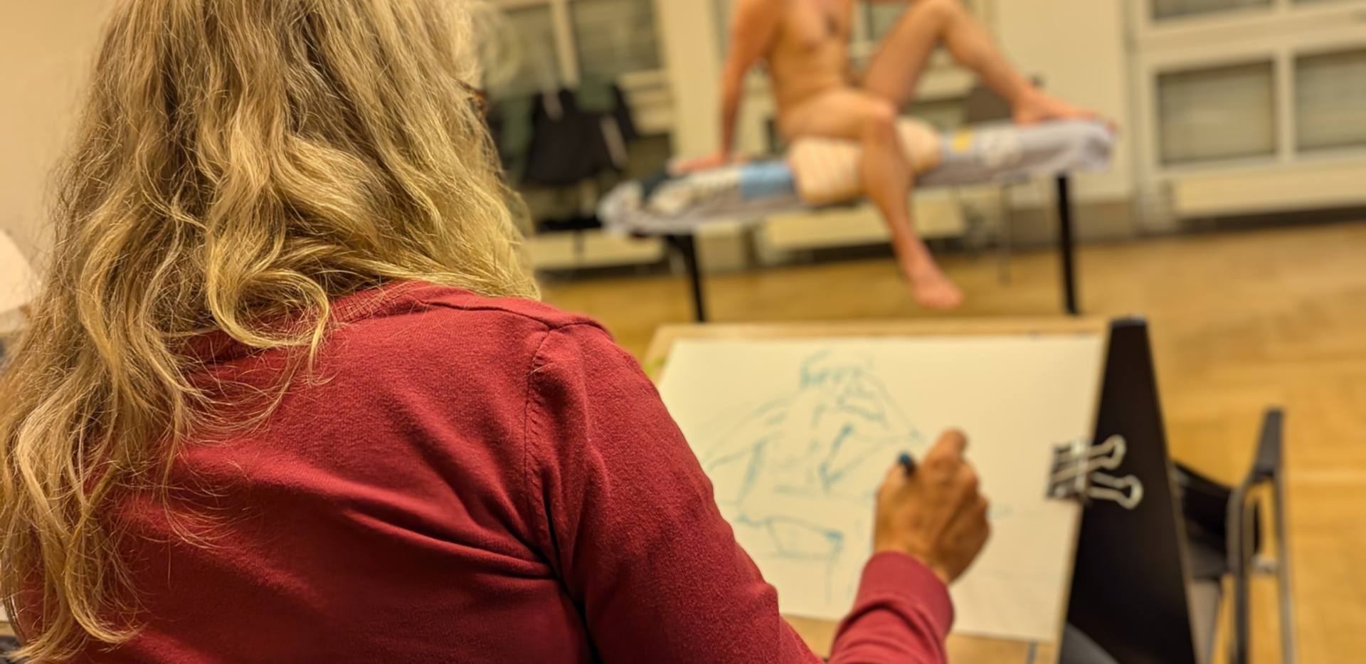 Aktkurs, Zeichnende Teilnehmerin mit Aktmodel im Hintergrund, Foto HJM