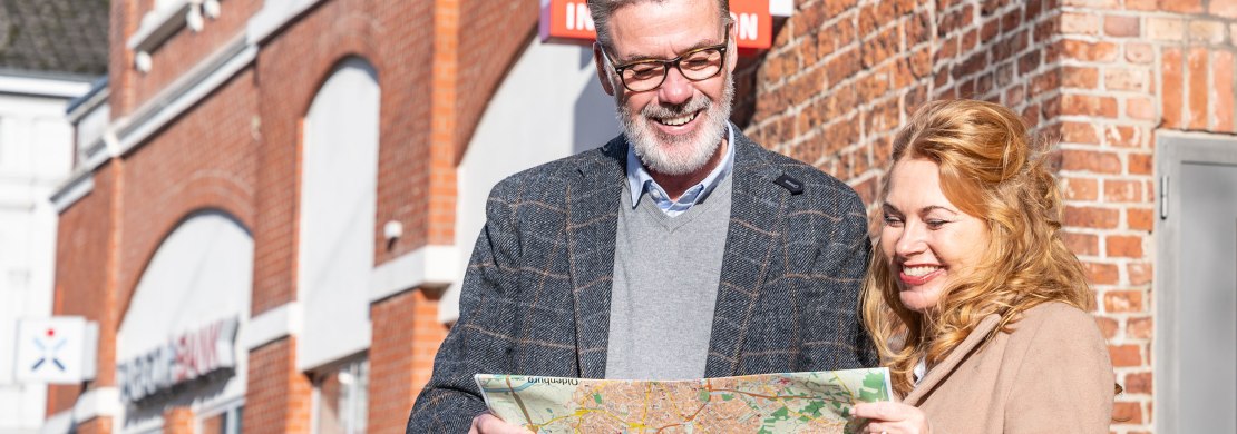 Gäste mit einem Oldenburg Stadtplan vor der Touristinformation.