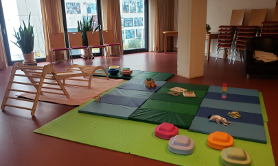 in unserer gast:STUBE gibt es auf dem Boden Matten für kleine Kinder, Klettermöglichkeiten, diverses Spielzeug und Platz für Bewegung. Auf der Angrenzenden Küchenzeile steht Kaffee und Tee bereit für gemütliches Verweilen.