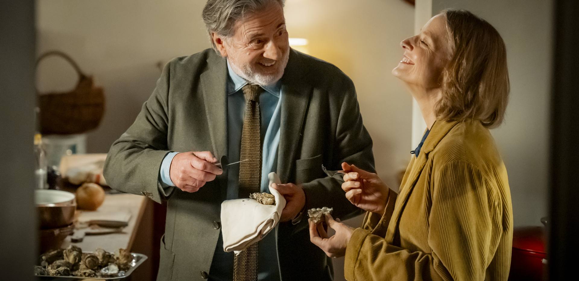 In der Mitte ist eine männlich gelesene Person, die zu einer weiblich gelesenen Person redet, die rechts steht. Beide lachen. Die männlich gelesene Person hat eine Nadel und ein Tuch in der Hand. In der Mitte ist eine männlich gelesene Person, die zu einer weiblich gelesenen Person redet, die rechts steht. Beide lachen. Die männlich gelesene Person hat eine Nadel und ein Tuch in der Hand.