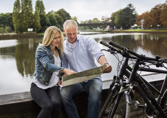 Fahrradfahrer machen Pause am Hafen in Oldenburg und orientieren sich mithilfe einer Fahrradkarte.