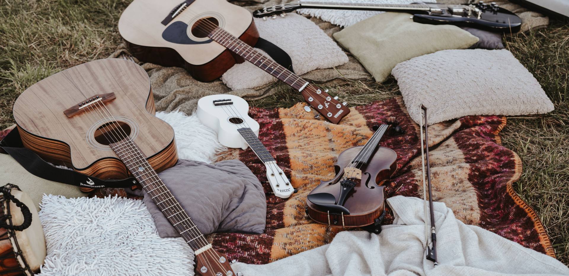 Stillleben von Musikinstrumenten, die im Freien auf Decken und Kissen angeordnet sind. Foto: Jakub Tabisz/Pexels Stillleben von Musikinstrumenten, die im Freien auf Decken und Kissen angeordnet sind. Foto: Jakub Tabisz/Pexels