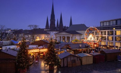Blick auf den Weihnachtsmarkt Oldenburg auf dem Schlossplatz mit der St. Lamberti-Kirche im Hintergrund.