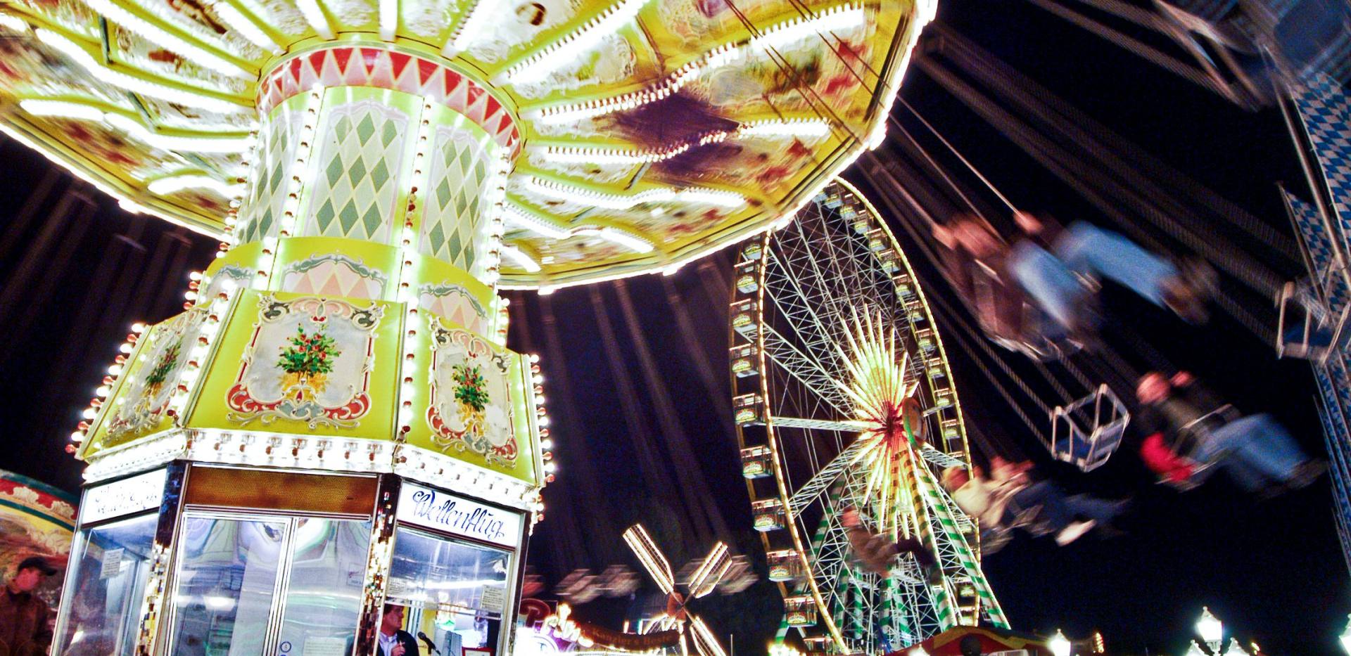 Nachtaufnahme mit beleuchtetem Kettenkarussell und Riesenrad auf dem Oldenburger Kramermarkt.