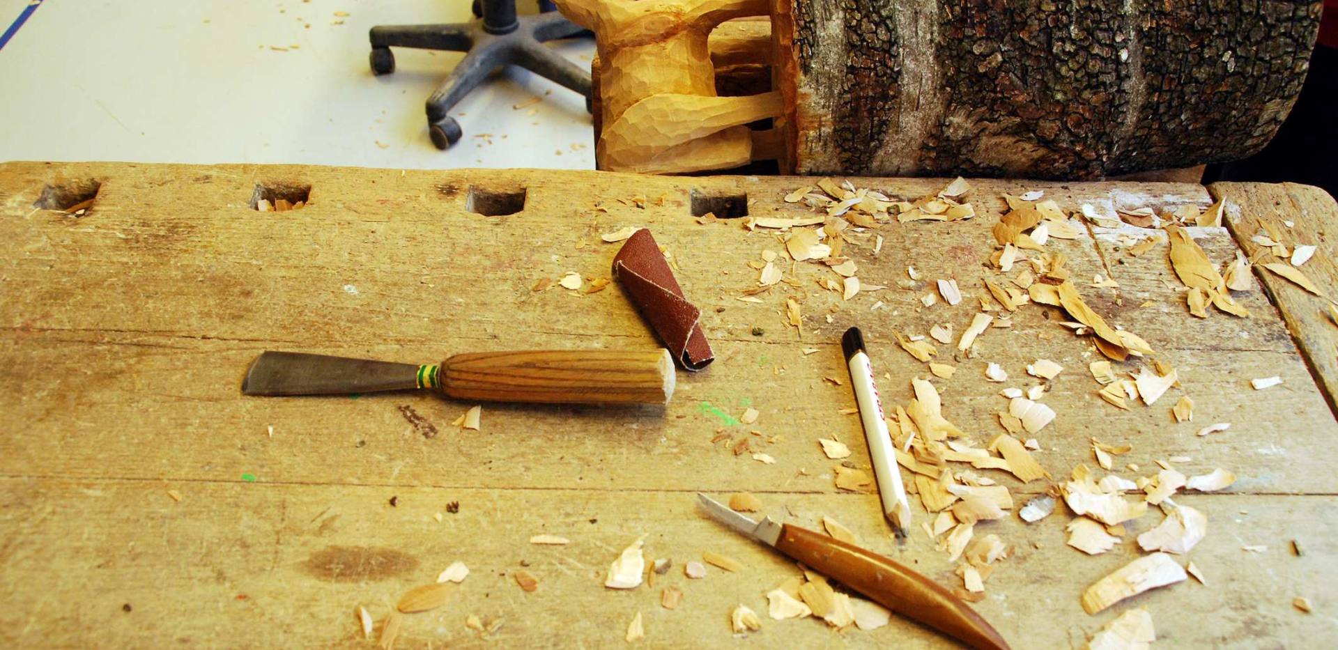 Auf dem Foto befinden sich eine Holzskulptur und einige Werkzeuge.