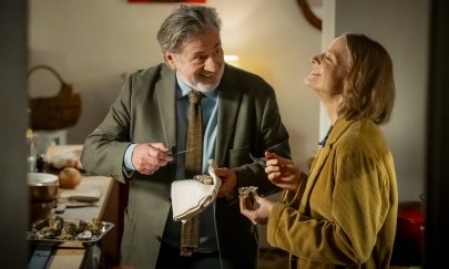 In der Mitte ist eine männlich gelesene Person, die zu einer weiblich gelesenen Person redet, die rechts steht. Beide lachen. Die männlich gelesene Person hat eine Nadel und ein Tuch in der Hand. In der Mitte ist eine männlich gelesene Person, die zu einer weiblich gelesenen Person redet, die rechts steht. Beide lachen. Die männlich gelesene Person hat eine Nadel und ein Tuch in der Hand.