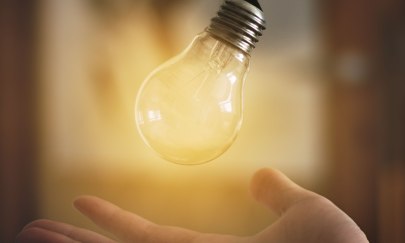 leuchtende Glühbirne wird von einer Hand aufgefangen leuchtende Glühbirne wird von einer Hand aufgefangen