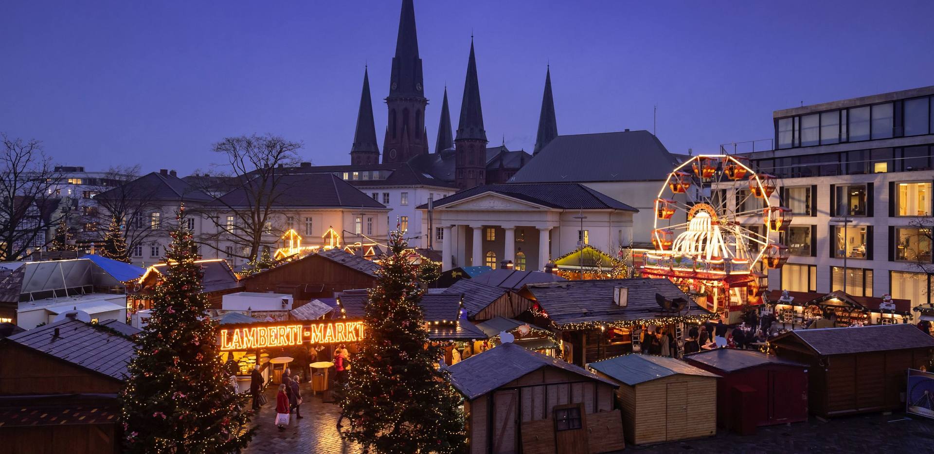 Oldenburger Weihnachtsmarkt auf dem Schlossplatz mit der Schlosswache und der St. Lamberti-Kirche im Hintergrund.