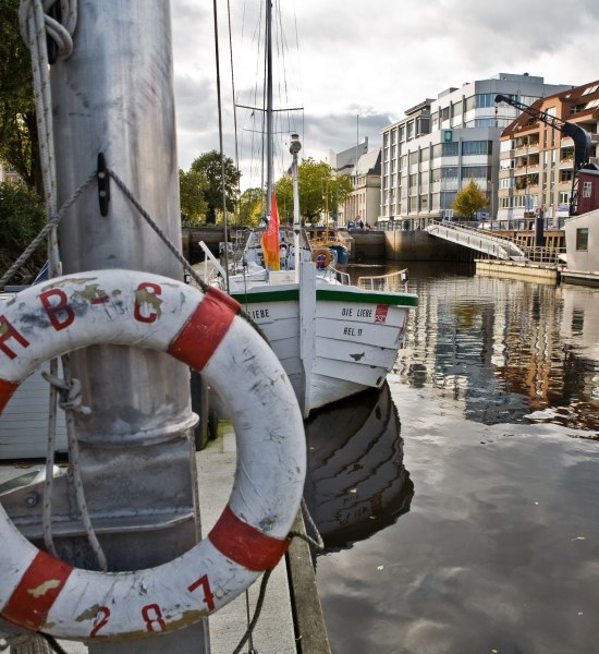 Blick auf den Stadthafen mit einem Börteboot im Hintergrund.