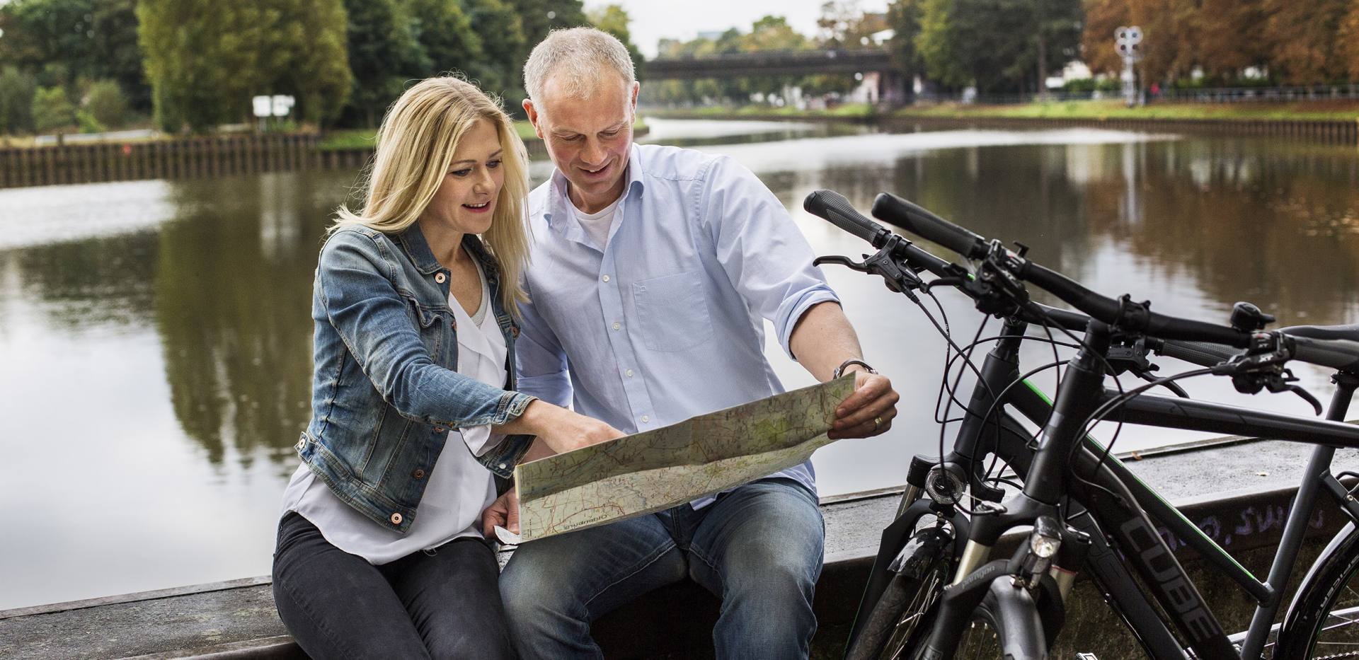 Fahrradfahrer machen Pause am Hafen in Oldenburg und orientieren sich mithilfe einer Fahrradkarte.