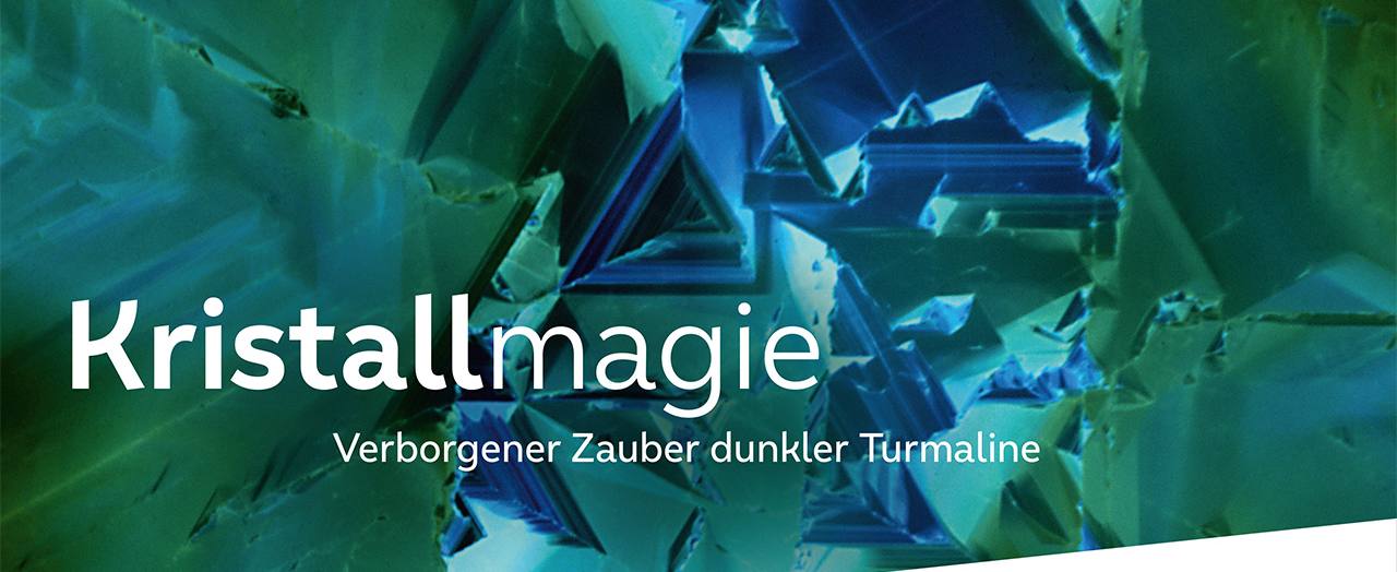 Das Bild zeigt die innere Struktur und Farbe eines Turmalinkristalls. Im Vordergrund ist der Titel der Ausstellung "Kristallmagie. Verborgener Zauber dunkler Turmaline" zu lesen. Die Ausstellung läuft vom 21. März bis zum 13. September. Das Bild zeigt die innere Struktur und Farbe eines Turmalinkristalls. Im Vordergrund ist der Titel der Ausstellung "Kristallmagie. Verborgener Zauber dunkler Turmaline" zu lesen. Die Ausstellung läuft vom 21. März bis zum 13. September.