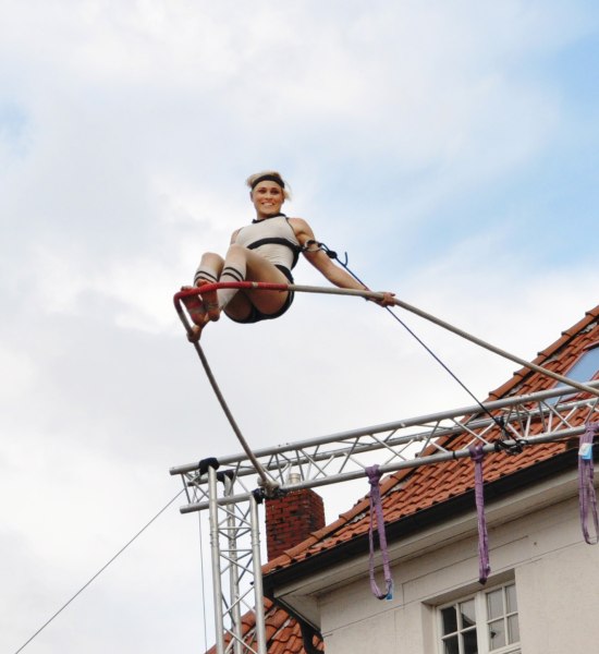 Eine Künstlerin fliegt am Trapez über den Julius-Mosen-Platz in Oldenburg.
