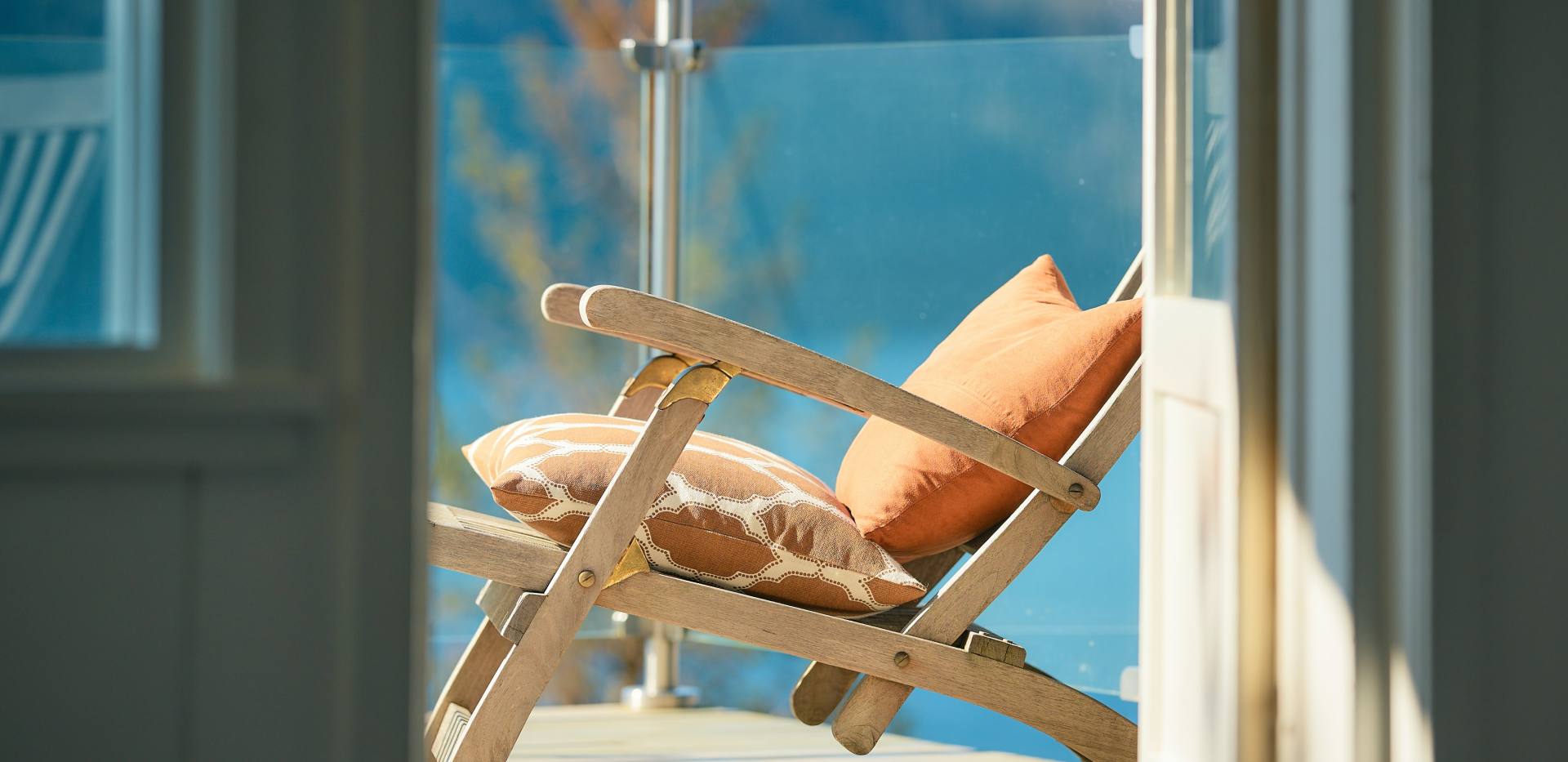 Ein Stuhl steht auf einem Balkon und die Sonne scheint.