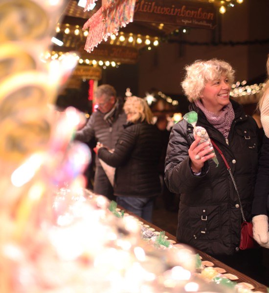 Zwei Personen schauen sich gemeinsam die Auslage an eine Stand auf dem Weihnachtsmarkt Oldenburg an.