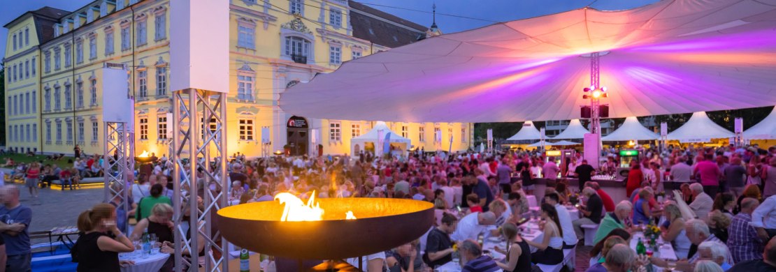 Vor dem Oldenburger Schloss sitzen viele Besucher bei der Veranstaltung Kochen am Schloss unter einem großen Sonnentuch.