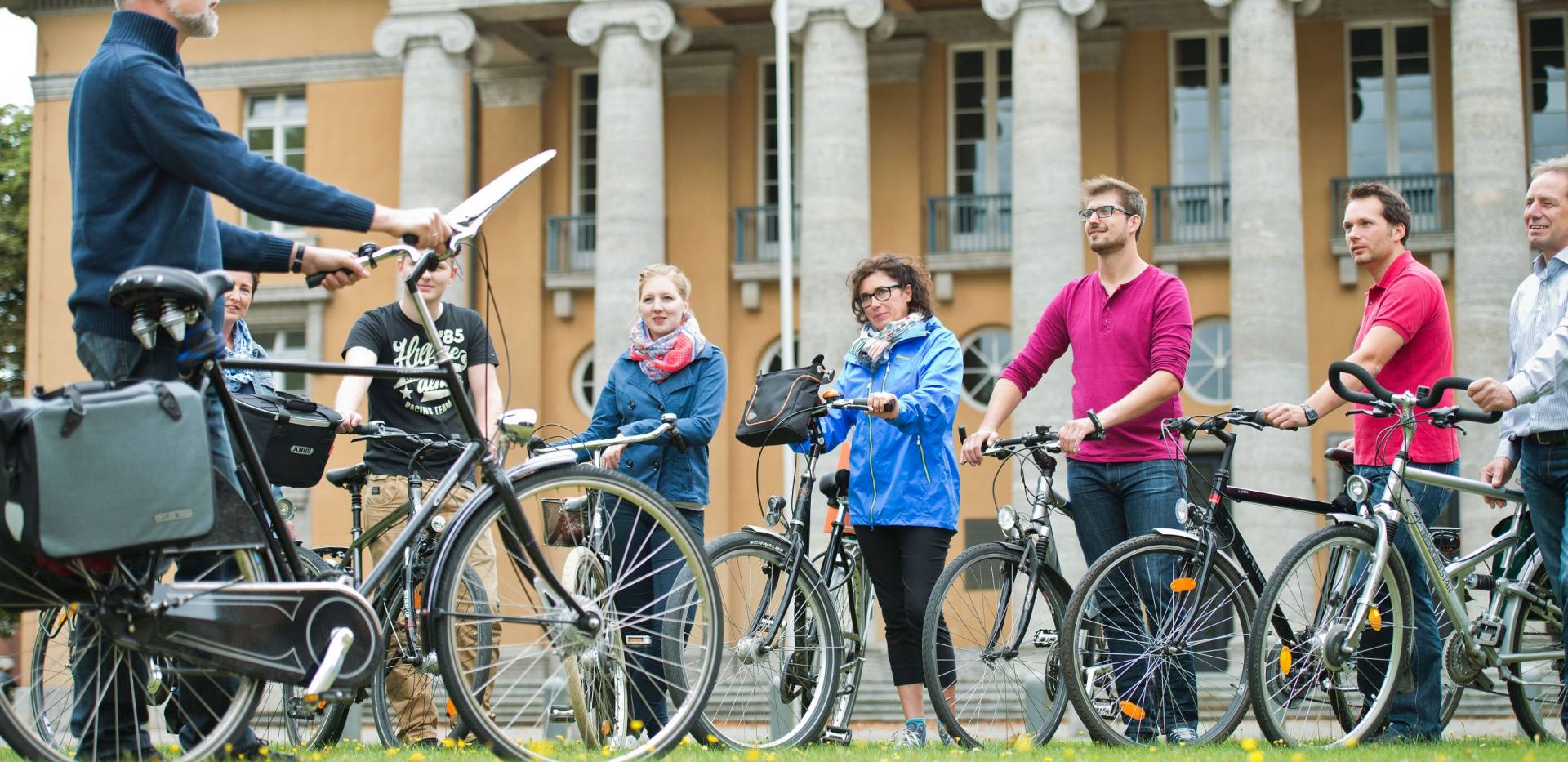 Eine Gruppe Radfahrender bei einer Stadtführung per Rad vor dem Alten Landtag Oldenburg.