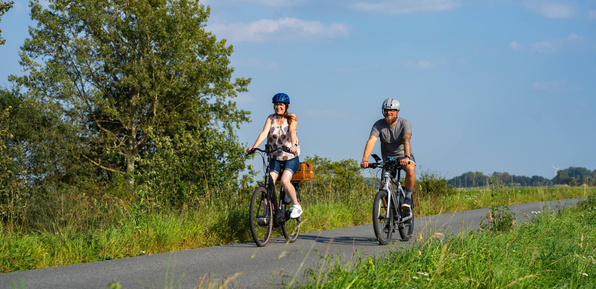 Ein radfahrendes Pärchen auf einem Radweg in der Wesermarsch. Die RadPartie ist eine DIY-Fotoerlebnistour durch Oldenburg und die Wesermarsch.