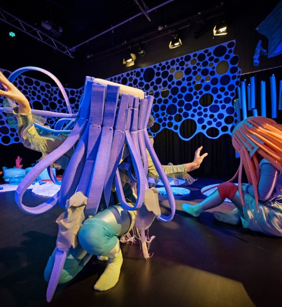 Zwei Performerinnen mit H&uuml;ten auf einer B&uuml;hne in Unterwasseratmosph&auml;re