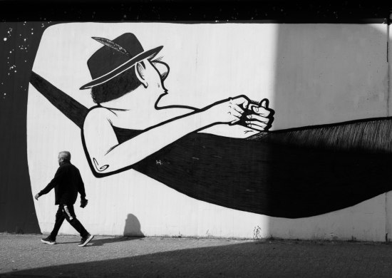 Street Art Motiv eines Mannes in einer Hängematte mit Fußgänger in schwarz weiß