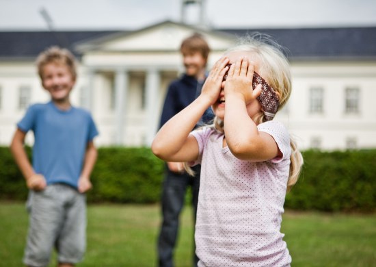 Kinder spielen Blinde Kuh vor einer Sehenswürdigkeit.