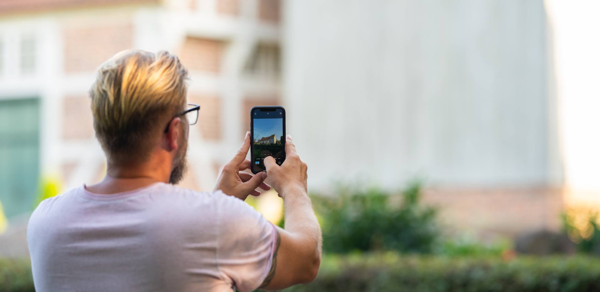 Ein Teilnehmer der DIY-Fotoerlebnistour RadPartie nimmt mit seinem Smartphone eine Sehenswürdigkeit auf der Tour auf.