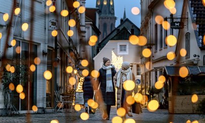 Zwei Frauen gehen durch die weihnachtlich beleuchtete Burgstraße in Oldenburg. 