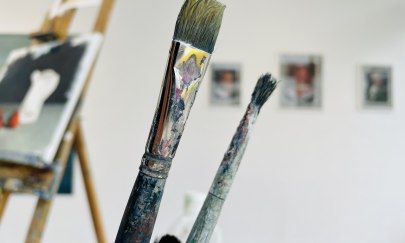 Auf dem Foto befinden sich einige Pinsel, im Hintergrund sieht man Gemälde. Auf dem Foto befinden sich einige Pinsel, im Hintergrund sieht man Gemälde.