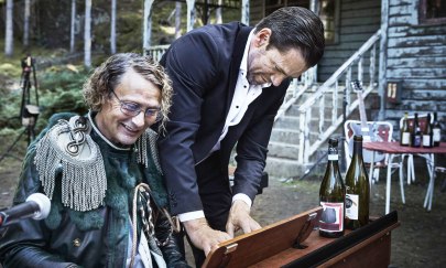 Auf dem Bild sind 2 Personen. Die linke Person sitzt vor einem Klavier und spielt. Die rechte Person steht und spielt ebenfalls auf dem Klavier. Beide sehen glücklich aus. Im Hintergrund steht ein Haus in einem Wald. Auf dem Bild sind 2 Personen. Die linke Person sitzt vor einem Klavier und spielt. Die rechte Person steht und spielt ebenfalls auf dem Klavier. Beide sehen glücklich aus. Im Hintergrund steht ein Haus in einem Wald.