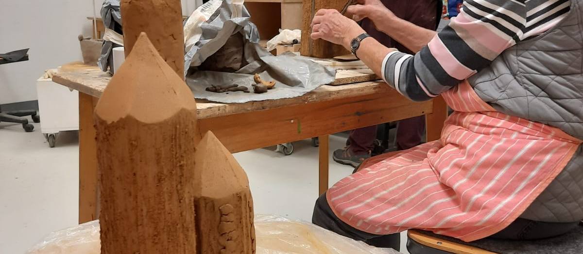 Auf dem Foto sieht man, wie eine Person an einer Tonskulptur arbeitet.