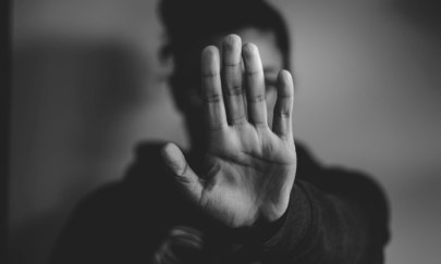 Eine als weiblich gelesene Person hält ihren linken Arm ausgetreckt vor sich auf Gesichtshöhe; die Handfläche zeigt nach vorn. Es ist eine abwehrende Haltung. Eine als weiblich gelesene Person hält ihren linken Arm ausgetreckt vor sich auf Gesichtshöhe; die Handfläche zeigt nach vorn. Es ist eine abwehrende Haltung.