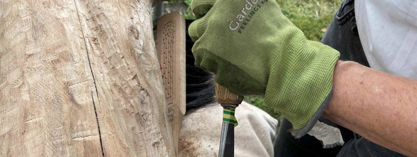 Auf dem Foto wird an einer Holzskulptur gearbeitet.