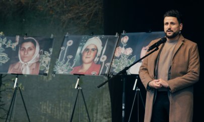 Ein Mann steht auf einer Bühne mit Bildern von Frauen im Hintergrund.