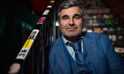 Bernd Begemann trägt Anzug und Krawatte und sizt auf einer Treppe.