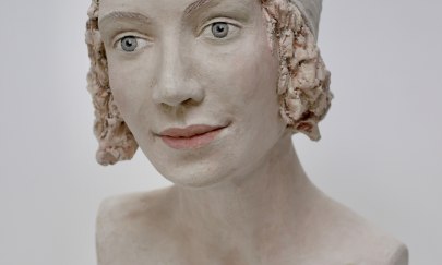 Eine keramische Büste mit heller Glasur, offenen Haaren unter einer Mütze, die in die Ferne blickt. Eine keramische Büste mit heller Glasur, offenen Haaren unter einer Mütze, die in die Ferne blickt.