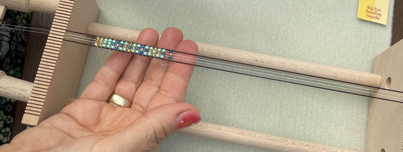 Auf dem Bild ist zu sehen, wie jemand Perlen webt.