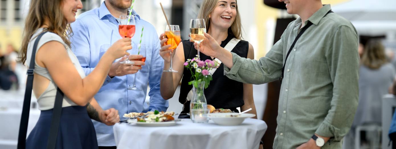 Eine Freundesgruppe beim Ansto&szlig;en bei Kochen am Schloss Oldenburg