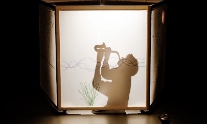 Mann als Schattenspiel auf einer Leinwand sichtbar und spielt Saxophon Mann als Schattenspiel auf einer Leinwand sichtbar und spielt Saxophon