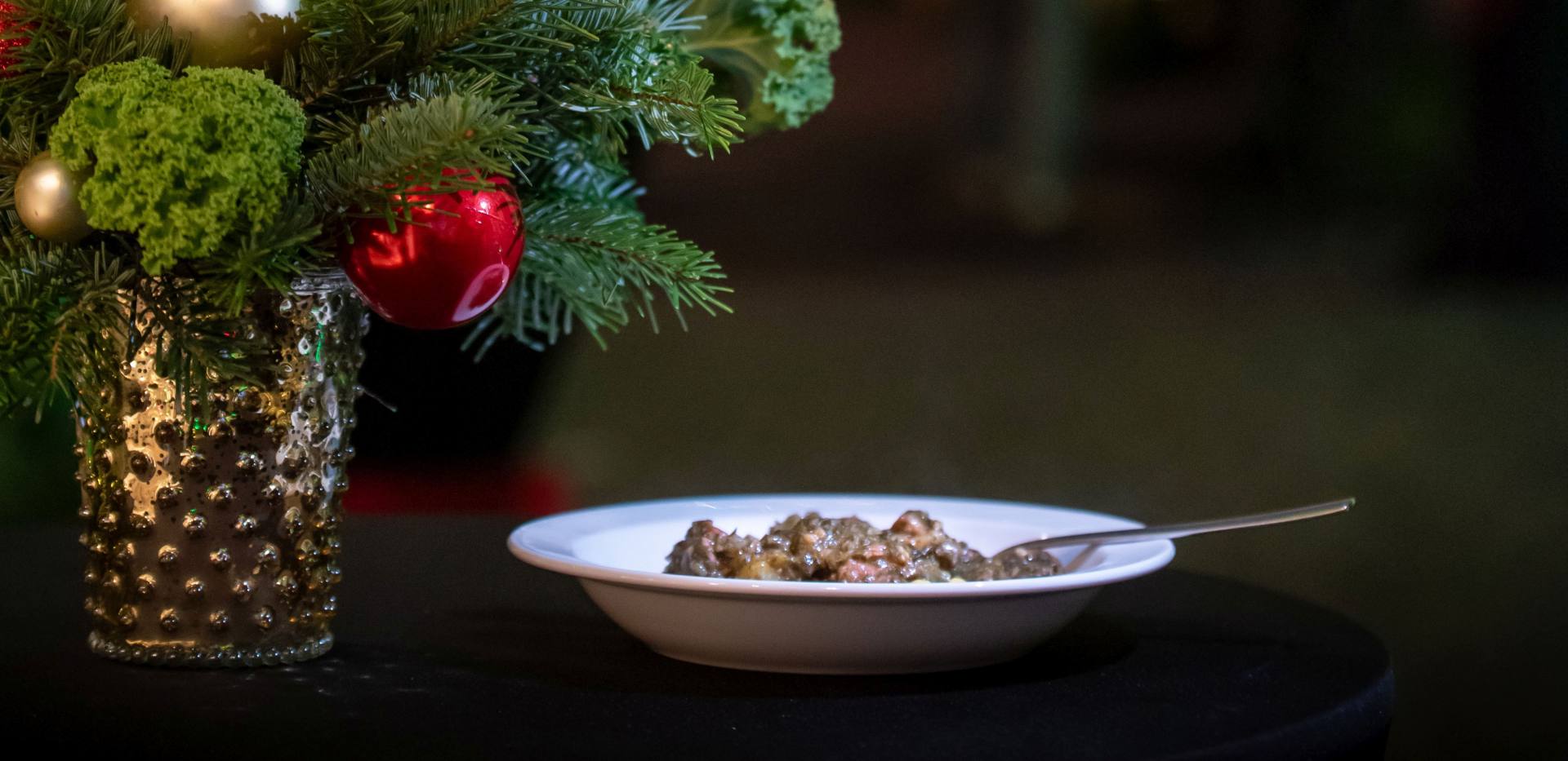 Ein Teller mit Grünkohleintopf neben einem Adventsgesteck und dem weihnachtlich geschmückten Lappangang in Oldenburg. Ein Teller mit Grünkohleintopf neben einem Adventsgesteck und dem weihnachtlich geschmückten Lappangang in Oldenburg.