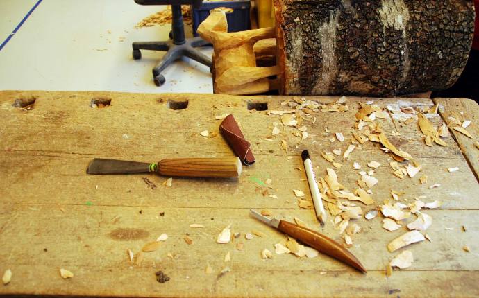 Auf dem Foto befinden sich eine Holzskulptur und einige Werkzeuge.