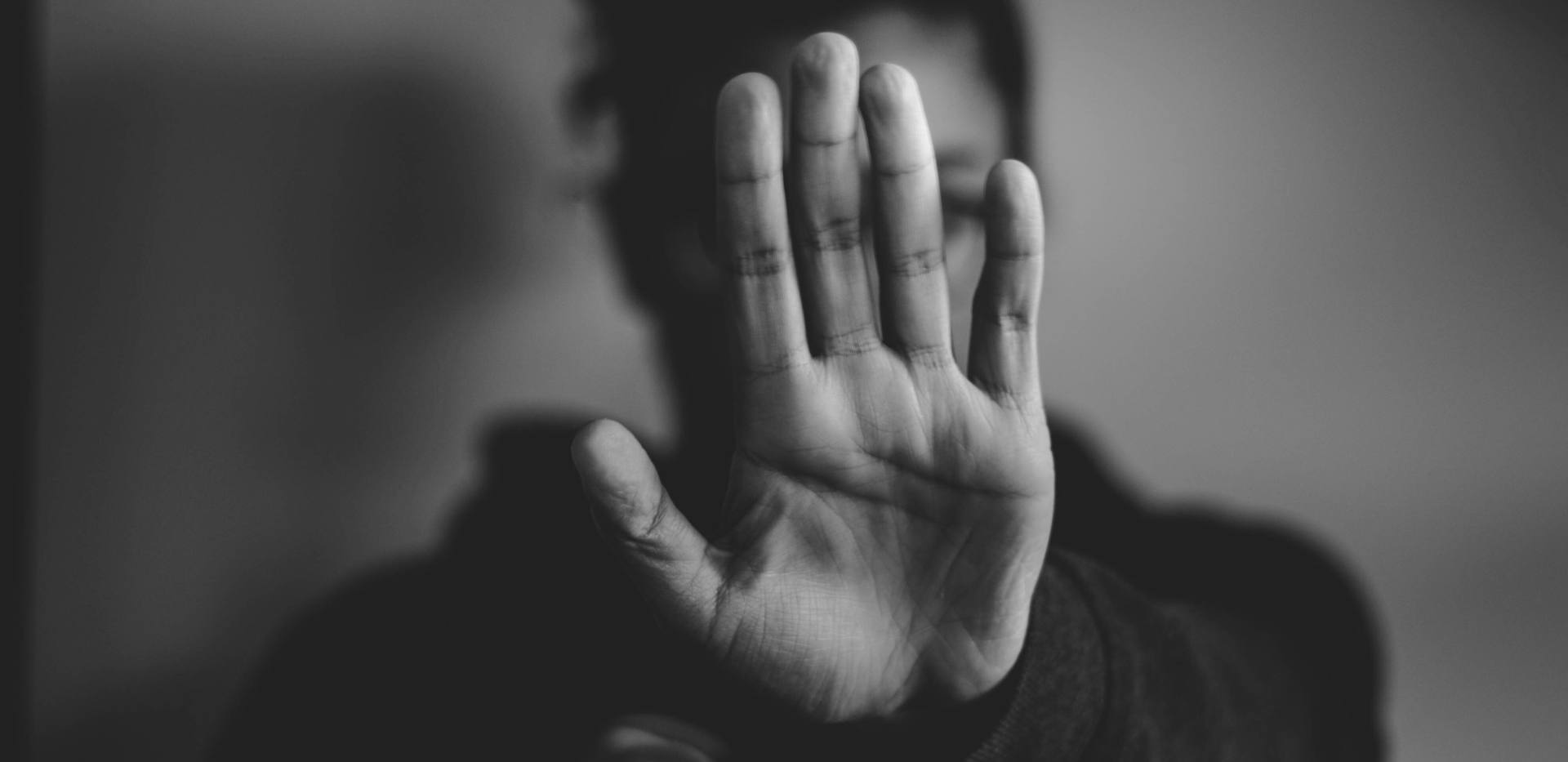 Eine als weiblich gelesene Person hält ihren linken Arm ausgetreckt vor sich auf Gesichtshöhe; die Handfläche zeigt nach vorn. Es ist eine abwehrende Haltung. Eine als weiblich gelesene Person hält ihren linken Arm ausgetreckt vor sich auf Gesichtshöhe; die Handfläche zeigt nach vorn. Es ist eine abwehrende Haltung.